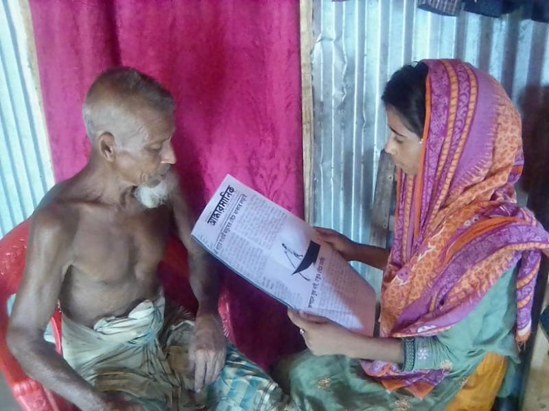 গ্রামের দৃষ্টিশক্তি হারানো প্রবীণ আবদুল হামিদ বাঘাকে পত্রিকা পড়ে শোনাচ্ছেন তার নাতনি সোনিয়া আক্তার