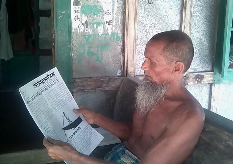 গ্রামবাসী তাল গাছের রস সংগ্রহকারী মো. সানাউল্লাহ, পত্রিকা পাঠে তার মনযোগ